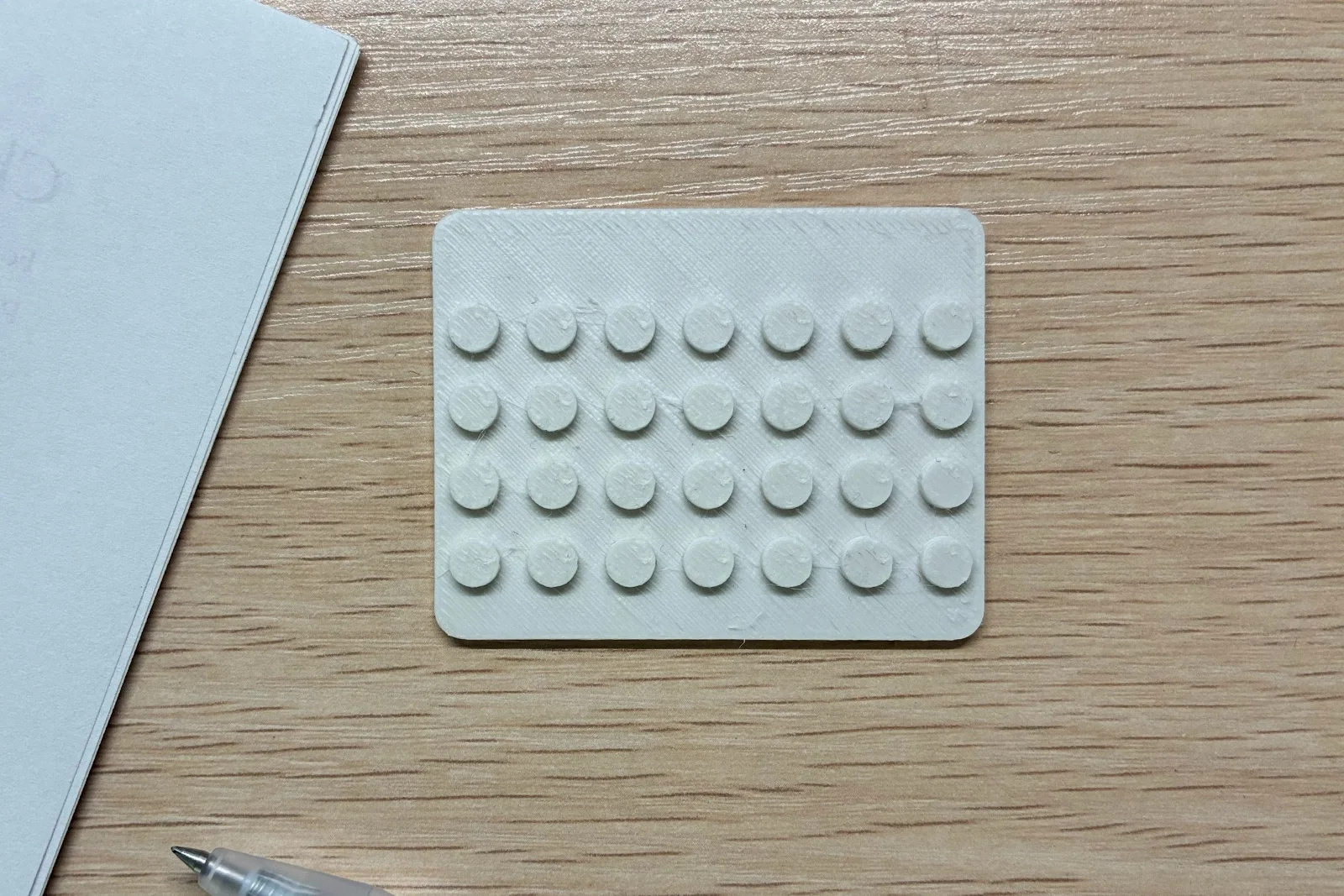 An empty white custom baseplate rests on a wooden desk.
