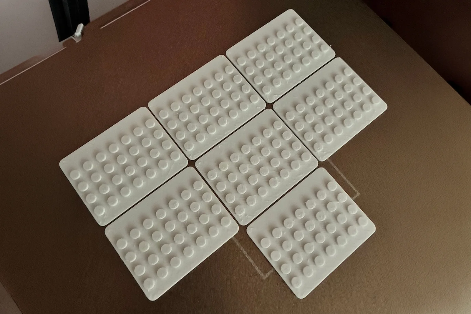 Seven empty white baseplates arranged on a tabletop.