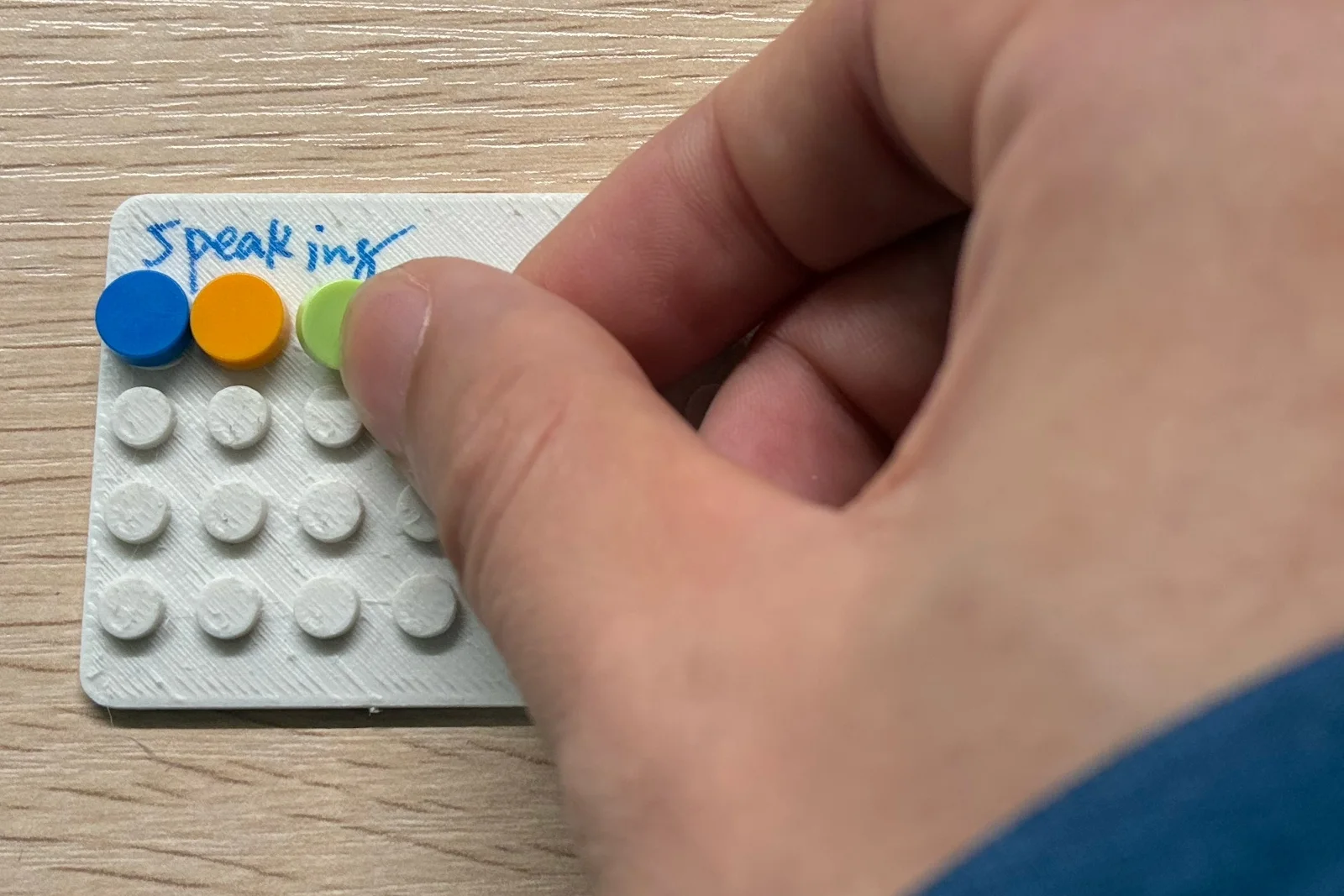 Louis presses a colored brick onto a small baseplate labeled Speaking.